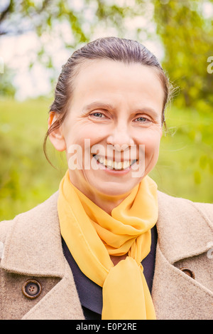 Portrait of smiling businesswoman avec un manteau et une écharpe jaune Banque D'Images