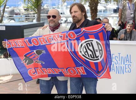 Cannes, France. 18 mai, 2014. Scénariste argentin Fabian Casas (L) et Danois Viggo Mortensen acteur américain à tenir le drapeau de la San Lorenzo de Almagro football club lors d'une séance de photos pour le 'Jauja' à la 67ème Festival du Film de Cannes, France, le 18 mai 2014. Le film est présenté dans la section Un Certain Regard du Festival qui aura lieu du 14 au 25 mai. Credit : Ye Pingfan/Xinhua/Alamy Live News Banque D'Images