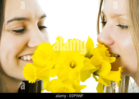 Deux jeunes filles l'odeur d'un bouquet d'un narcisse. Le contexte isolé Banque D'Images