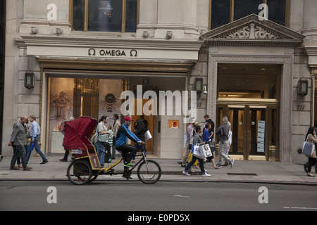 Pedicab & piétons sur la 5e Avenue à Manhattan, en passant l'Omega watches store. Banque D'Images