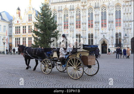 Les touristes équitation dans un cheval et un chariot passé l'hôtel de ville, sur le Burg à Bruges/Brugge, au moment de Noël, en Belgique, Europe Banque D'Images