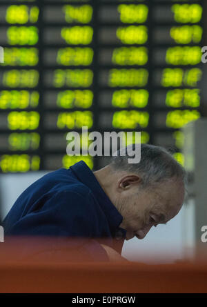 (140519) -- HANGZHOU, 19 mai 2014 (Xinhua) -- Un investisseur semble élevé grâce à des informations dans un hall commercial d'une société de valeurs mobilières à Hangzhou, capitale de la Chine de l'est la province du Zhejiang, le 19 mai 2014. Actions chinois fermé plus de 1 pour cent de moins le lundi, avec l'indice Shanghai Composite Index bas 21,32 points, ou 1,05  %, pour finir à 2 005,18. La composante de Shenzhen a chuté de 90,68 points, ou 1,25 pour cent, pour clôturer à 7 151,49. (Xinhua/Chuanhao Han) (lfj) Banque D'Images