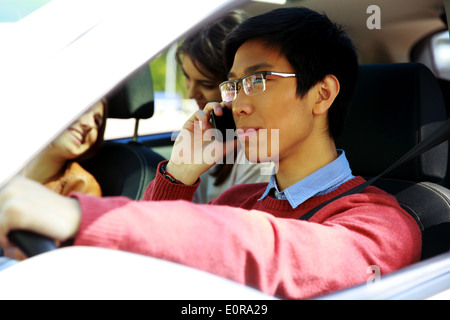 Young Asian man driving car and talking on mobile phone Banque D'Images