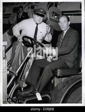 10 octobre 1959 - L'AÉROPORT INTERNATIONAL DE NEW YORK, 7 octobre 1959, Stirling Moss Ace pilote de course britannique prend le volant d'un tracteur à bagages  sauvages ralenti sur son arrivée ici à partir de Londres avant son départ à Los Angeles à bord d'un avion de la TWA. Moss course dans le Riverside, Californie Grand Prix parrainé par le Los Angeles Times Mirror. L'agent Daniel Sullivan TWA regarde sur. Moss est également prévu pour piloter une voiture de course dans un Watkins Glen, New York race le 18 octobre. Banque D'Images