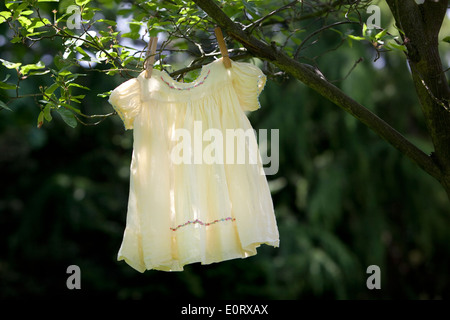 Vintage robe enfant jaune accroché à la branche d'un arbre. Banque D'Images