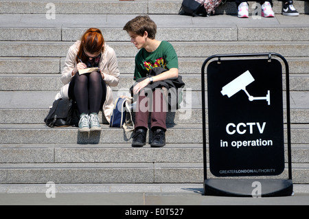 Londres, Angleterre, Royaume-Uni. Personnes à Trafalgar Square, assis sur les marches menant à la Galerie Nationale Banque D'Images