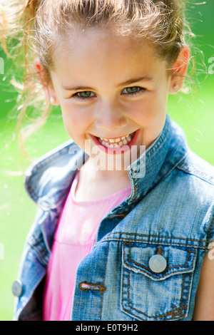Close up portrait of cute girl in park smiling. Banque D'Images