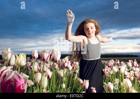 Jeune fille insouciante d'exécution par l'intermédiaire d'un champ de tulipes Banque D'Images