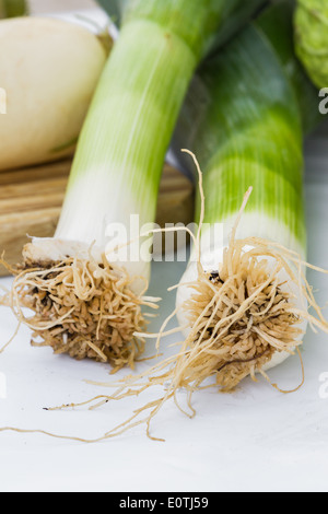 Poireaux frais biologique sur une nappe blanche à côté d'une planche à découper Banque D'Images