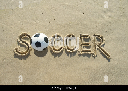 Soccer football manuscrites en message texte lettre capitale ensoleillée sur la plage de sable du Brésil Banque D'Images