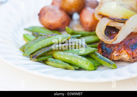 Un repas au barbecue de pois sugar snap, pommes de terre, l'oignon et le porc. Banque D'Images