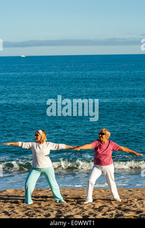 Deux femmes seniors faisant les exercices de yoga sur la plage. Banque D'Images