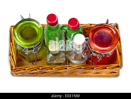 Bac en osier avec des pots en verre vides et peu de bouteille de verre, isolé sur fond blanc Banque D'Images