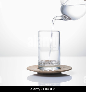 L'eau versée d'un pot d'un verre Banque D'Images