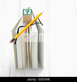 Un livre avec un crayon et un cube avec un point d'interrogation en haut de c Banque D'Images