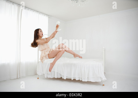 Une femme assise sur un lit de boire un café Banque D'Images