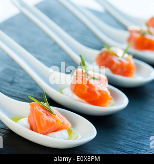 De nombreuses cuillères en porcelaine avec des morceaux de saumon fumé. Banque D'Images