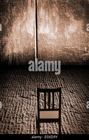 Une chaise vide dans une chambre abandonnée avec mur en béton et rugueux grungy-de-chaussée, peut-être mis en place pour l'interrogatoire. Image conceptuelle de la solitude, l'obscurité et la solitude. Banque D'Images