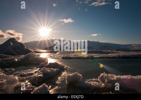 Coucher de soleil sur le Jokulsarlon - derniers rayons du soleil jettent une lueur chaude sur la glace flottante. Banque D'Images