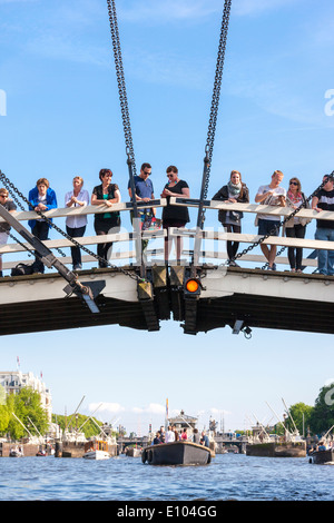 Amsterdam Magere Brug, Skinny Bridge, avec des gens touristes visiteurs observation des bateaux sur la rivière Amstel. Vu à partir de la croisière sur le canal. Banque D'Images