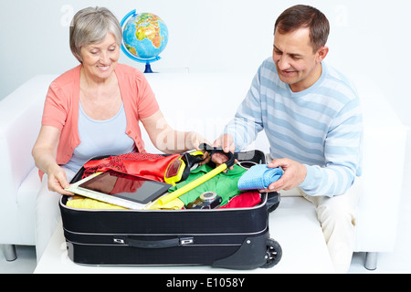 Portrait of happy senior couple packing suitcase Banque D'Images