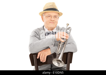 Représentant Senior holding trumpet assis sur une chaise Banque D'Images