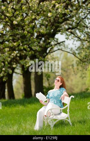 25 avril 2009 - 25 avril 2009 - red hair woman reading book sur banc blanc dans un pré ; shallow DOF Ã'Â© CTK/ZUM Banque D'Images