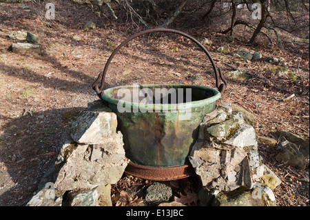 Ancien chaudron en cuivre reposant sur un feu de camp. Banque D'Images