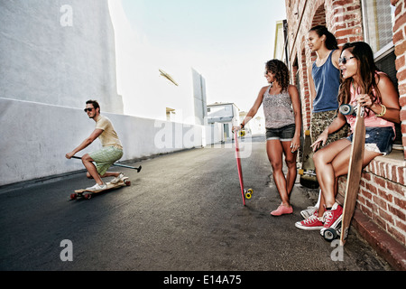 Friends riding longboards on city street Banque D'Images