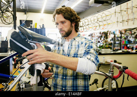 Caucasian man smiling in bicycle repair shop Banque D'Images