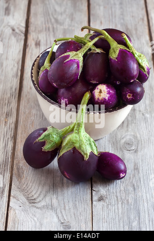 Taille bébé aubergines dans le bol en céramique de table en bois. Focus sélectif. Banque D'Images