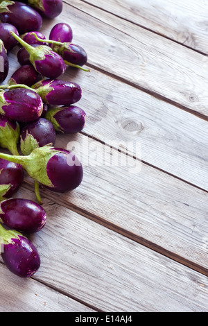 Taille bébé aubergines dans le bol en céramique de table en bois. Focus sélectif. Copie espace arrière-plan. Banque D'Images