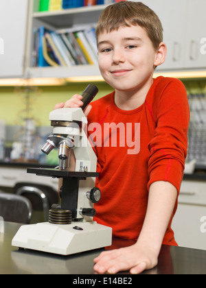 Young boy using microscope in chemistry lab Banque D'Images