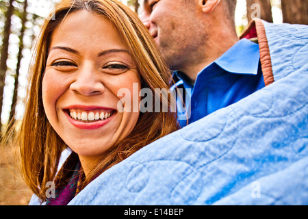 Hispanic couple wrapped in blanket in forest Banque D'Images