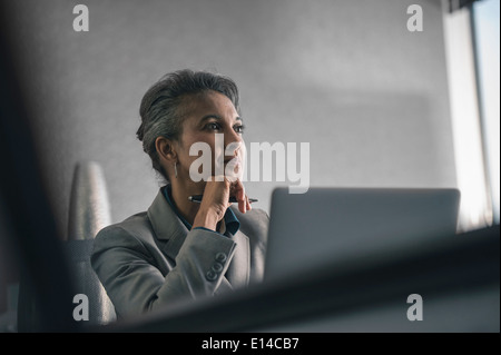 Mixed Race businesswoman using laptop in office Banque D'Images