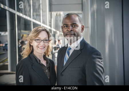 Business people smiling outside office building Banque D'Images