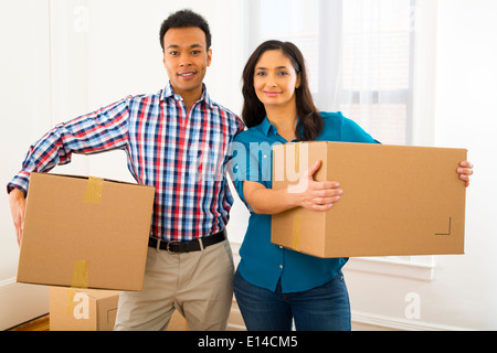 Mixed Race woman carrying cardboard boxes in new home Banque D'Images