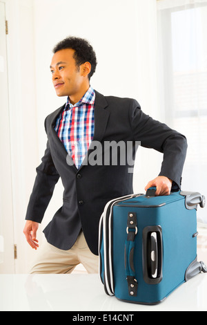 Mixed Race businessman carrying suitcase Banque D'Images