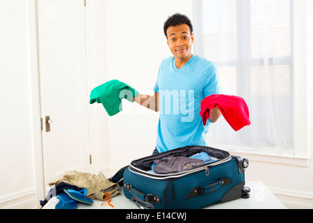 Mixed Race man packing suitcase Banque D'Images