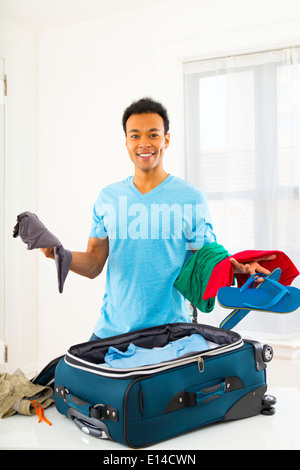 Mixed Race man packing suitcase Banque D'Images