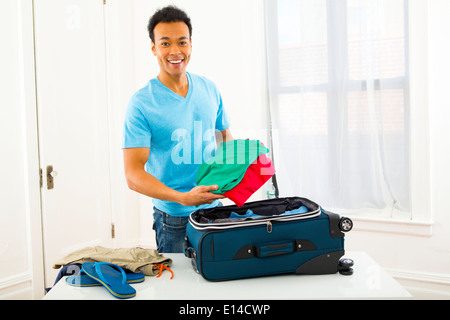 Mixed Race man packing suitcase Banque D'Images