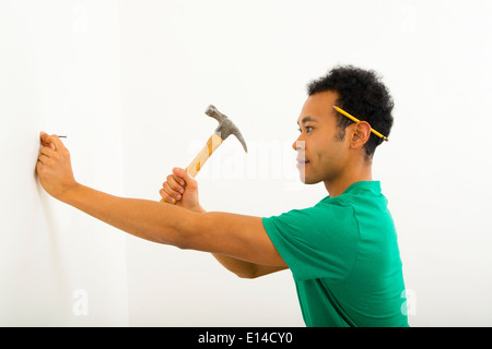 Mixed Race man hammering nail into wall