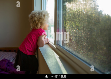 Mixed Race girl looking out window Banque D'Images