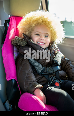 Mixed Race girl smiling in back seat of car Banque D'Images