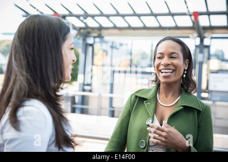 Businesswomen laughing on train platform Banque D'Images