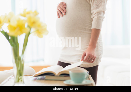 Pregnant Hispanic woman reading book Banque D'Images