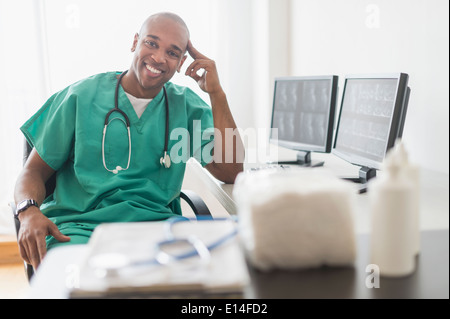 Black doctor smiling at computer in office Banque D'Images