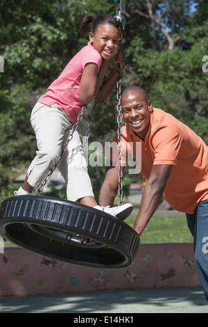 Père et fille jouer sur balançoire pneu Banque D'Images