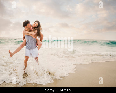 Caucasian couple playing on beach Banque D'Images