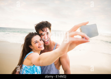 Caucasian couple taking pictures on beach Banque D'Images